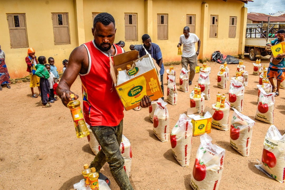 A volunteer places bottles of vegetable oil beside bags of rice at a distribution point in Nigeria.