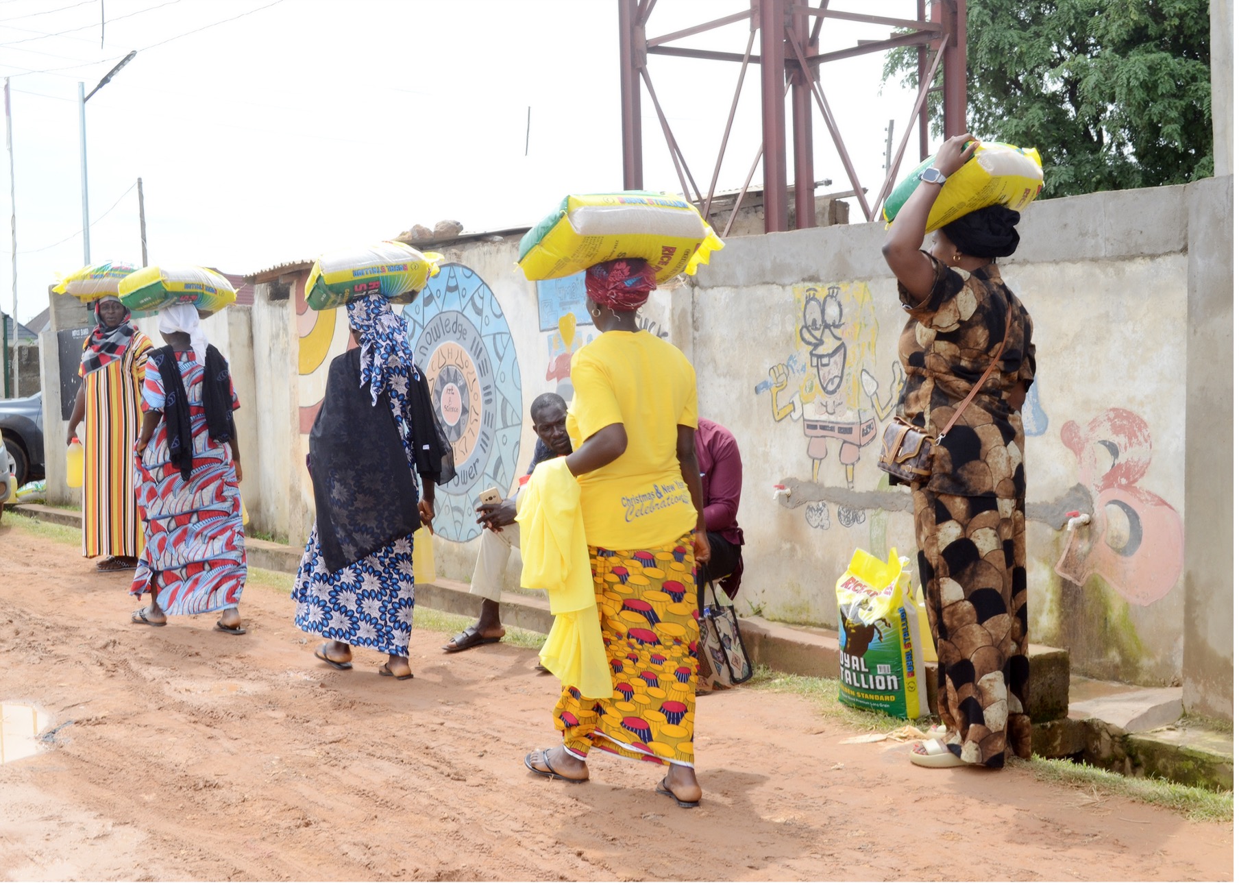 Beneficiaries leave a distribution site in Kaduna State carrying rice and vegetable oil.